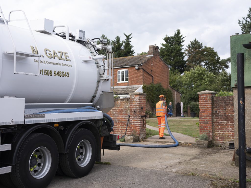 M. Gaze septic service truck with worker at a residential property
