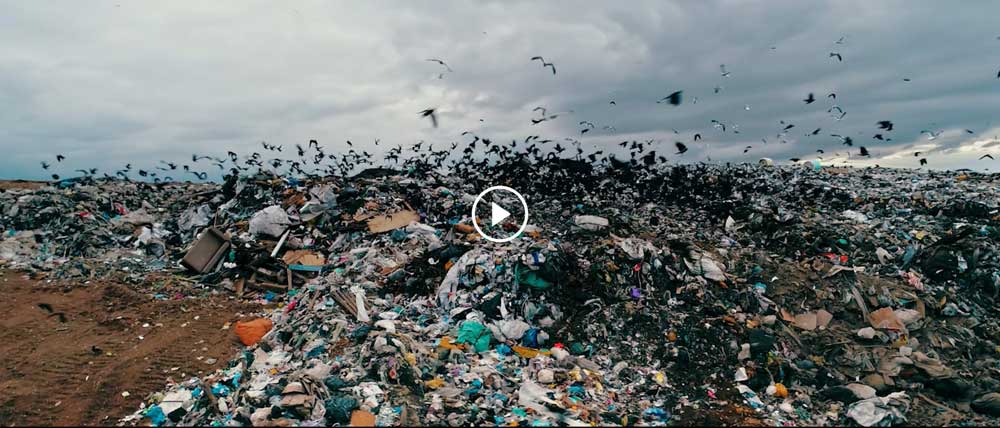 Landfill site with birds flying over large piles of mixed waste
